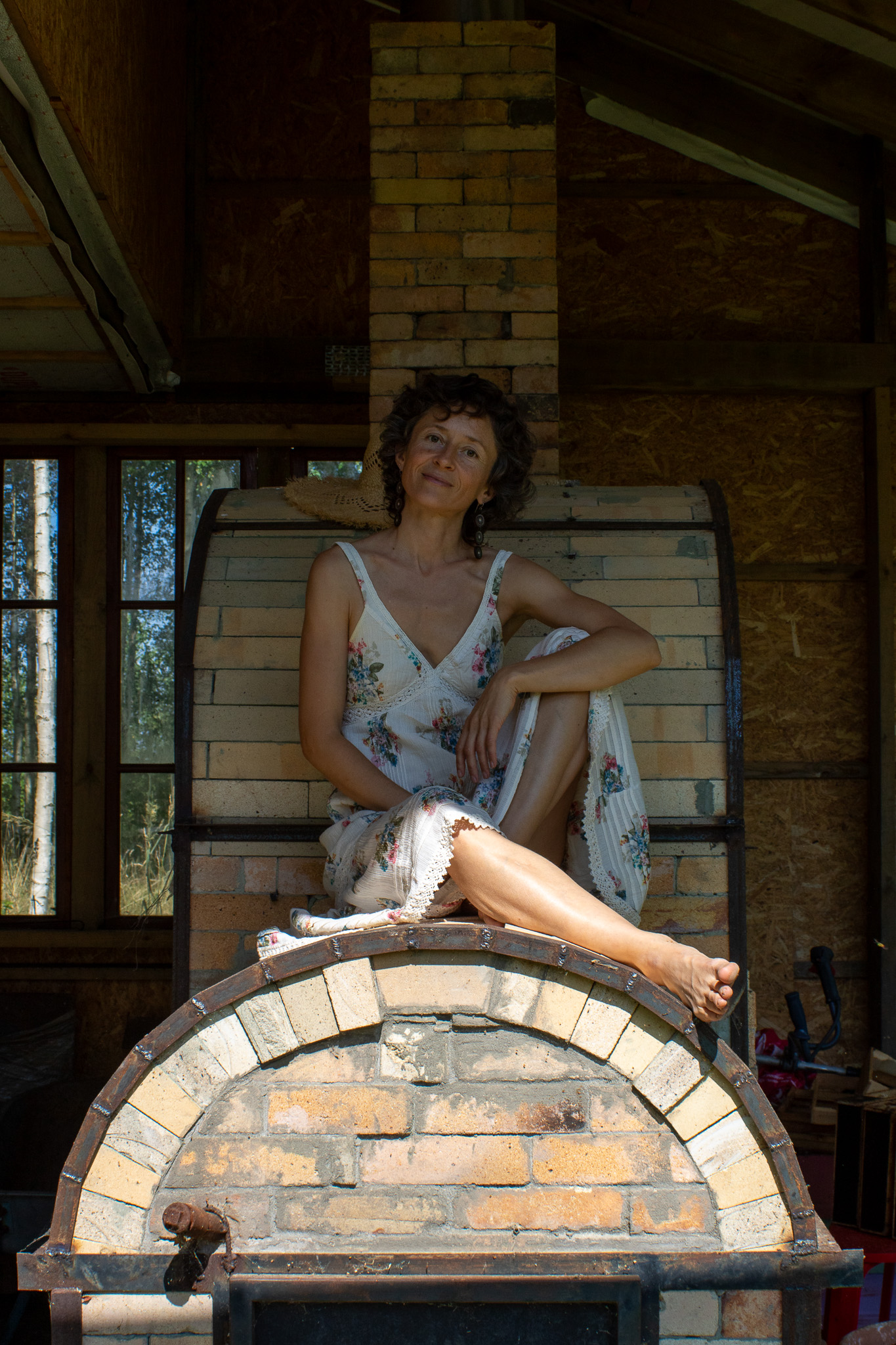 Victoria seated near a brick kiln in the ViciaBloom studio
