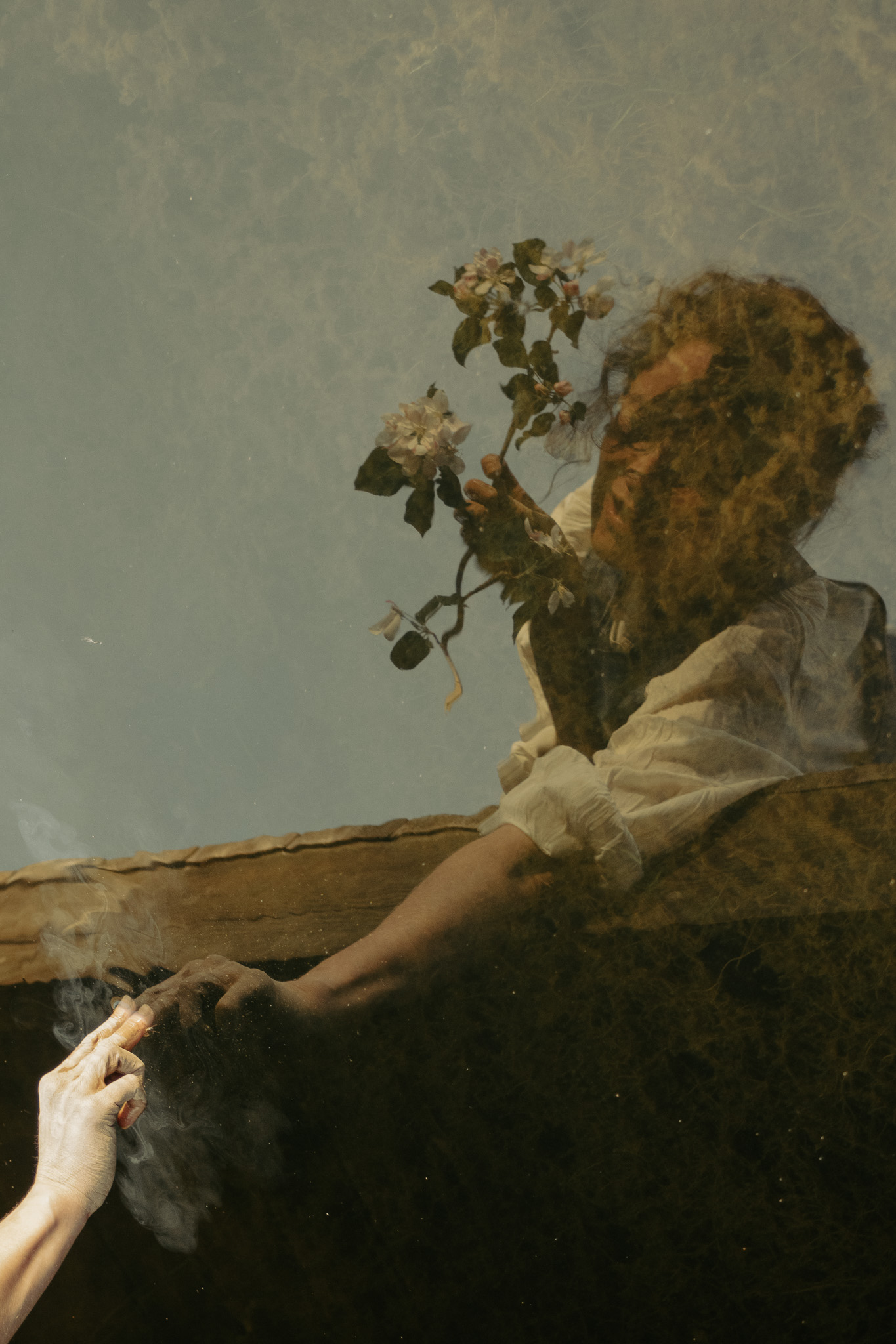 Reflection of Victoria holding blossoms with smoke and soft light